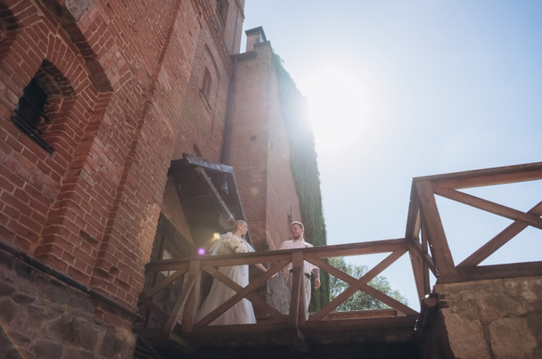 вид снизу на невесту и жениха перед входом в древний замок
 - Фото, изображение