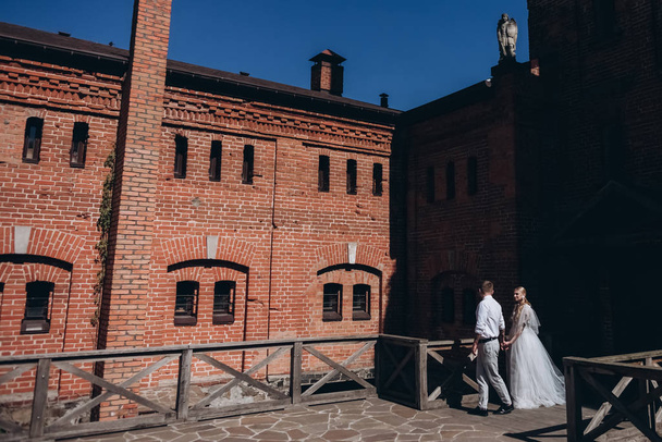 novia y novio caminando frente al edificio antiguo
 - Foto, Imagen