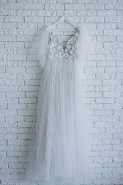 belle robe de mariée décorée de fleurs suspendues au mur de briques blanches
 - Photo, image