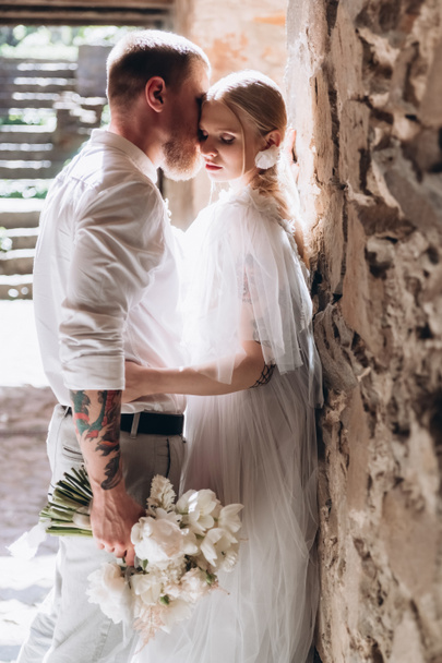 attractive young cuddling bride and groom inside of ancient building - Photo, Image