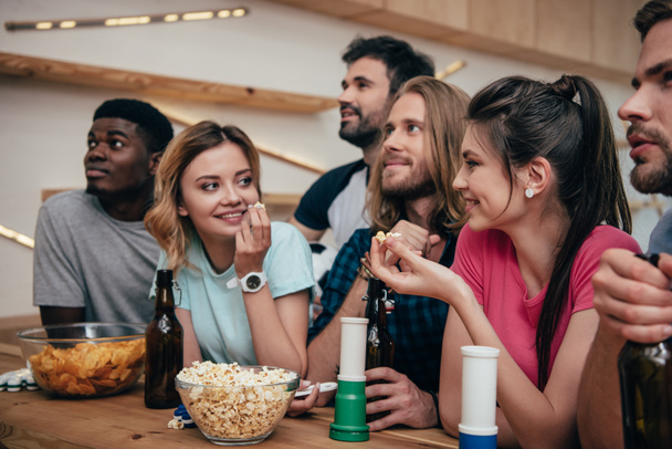 grupo multiétnico de amigos viendo el partido de fútbol en el bar con cuernos de ventilador, papas fritas, palomitas de maíz, cerveza y pelota de fútbol
  - Foto, Imagen