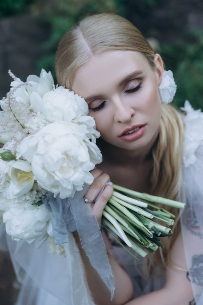 close-up portrait of beautiful young bride in dress with bouquet - Fotó, kép