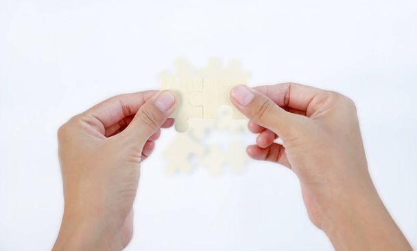 Closeup hands connecting jigsaw puzzle on white background - Fotografie, Obrázek