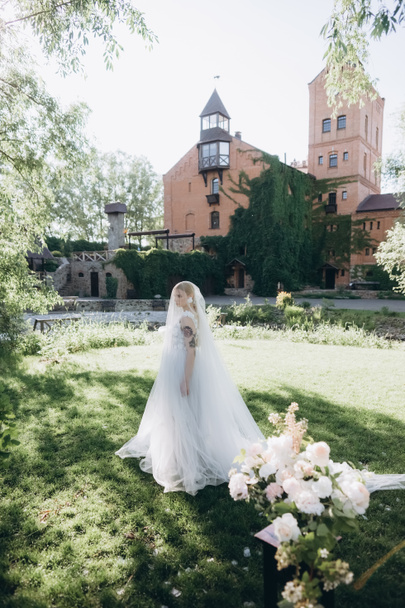 beautiful young bride in garden in front of ancient castle - Fotografie, Obrázek