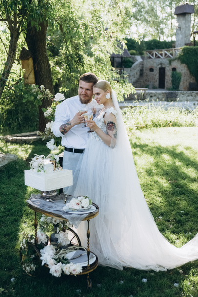 невеста и жених с бокалами шампанского и торт на стенде
 - Фото, изображение