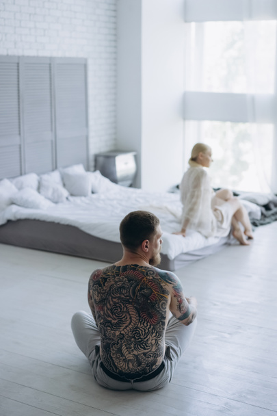 young couple sitting in bedroom separated after quarrel - Foto, afbeelding