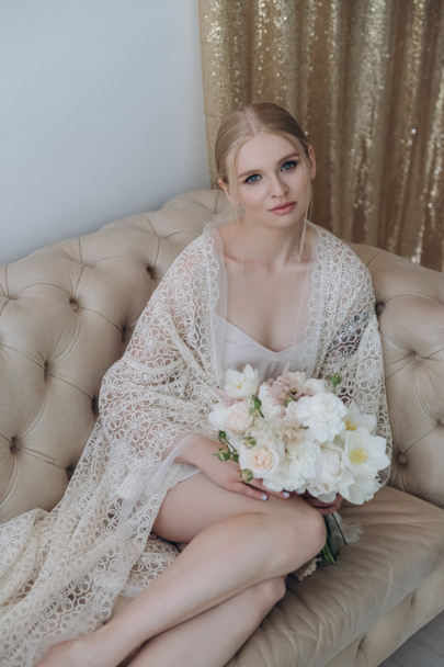 attractive young woman sitting on couch with bouquet - Foto, imagen