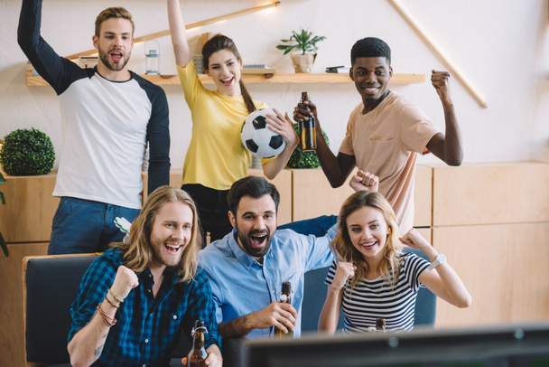  multicultural friends with soccer ball and beer bottles doing yes gestures during watch of  football match at home - Photo, Image