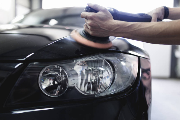 Man with orbital polisher in auto repair shop. Selective focus - Foto, afbeelding