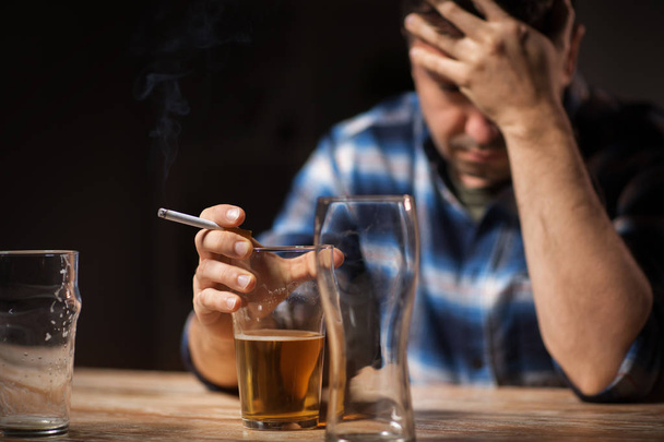drunk man drinking alcohol and smoking cigarette - 写真・画像