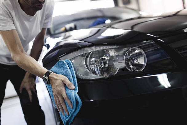 Man cleaning car with microfiber cloth, car detailing concept. Selective focus. - Zdjęcie, obraz
