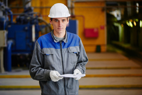 Portrait of factory worker holding documents in his hands inside the plant building - Фото, зображення