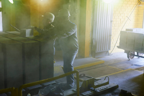 Arbeiter schieben einen Karren mit Ziegeln aus dem Ofen - Foto, Bild