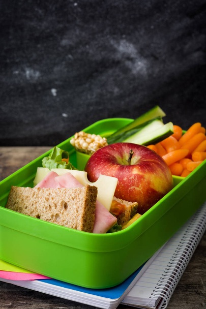 Healthy school lunch box: Sandwich, vegetables, fruit, juice and water on wooden table - Photo, Image