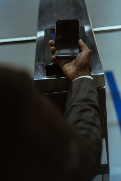 Обрезанный вид мужской руки со смартфоном, оплачивающим билет на общественный транспорт
 - Фото, изображение