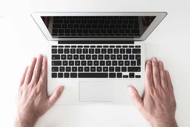 надмірний знімок обох рук людини, розміщених поряд з ноутбуком на білому столі
 - Фото, зображення