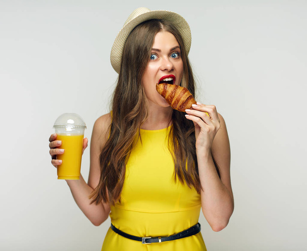 Young woman eating croissant with orange juice isolated on white background - Fotoğraf, Görsel