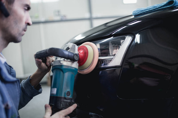 Man with orbital polisher in auto repair shop. Selective focus - Φωτογραφία, εικόνα