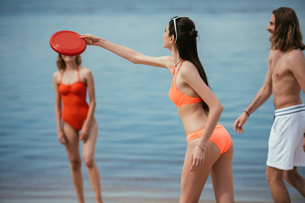 happy young people playing with flying disk on beach - Photo, Image