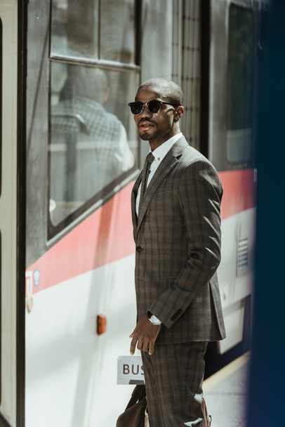 Молодий афроамериканець бізнесмен чекає поїзда на станцію - Фото, зображення