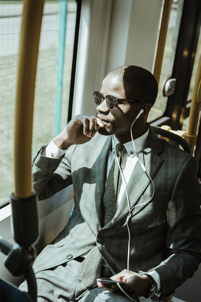 Empresario afroamericano con traje escuchando música mientras toma tren
 - Foto, imagen