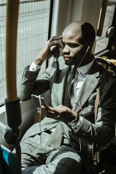 Empresario afroamericano con traje escuchando música mientras va a trabajar en tren
 - Foto, imagen