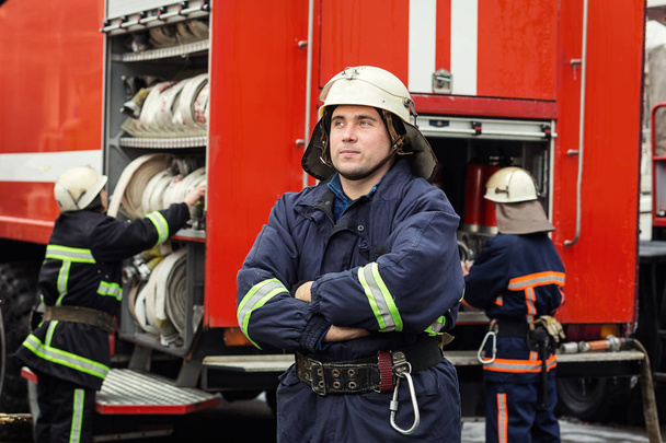 Palomies (palomies) toiminnassa seisoo lähellä paloauto. Hätätilanne. Suojelu, pelastus vaaroilta
. - Valokuva, kuva