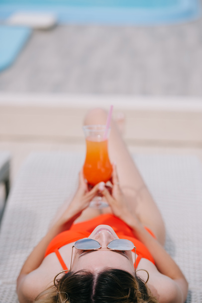enfoque selectivo de la chica en trajes de baño y gafas de sol celebración de cóctel y descanso en la playa
 - Foto, Imagen