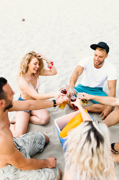 Group of attractive young people enjoying at beach, drinking and toasting. - Foto, immagini