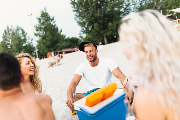 Groep aantrekkelijke jongeren die genieten aan het strand, drinken en toasten. - Foto, afbeelding