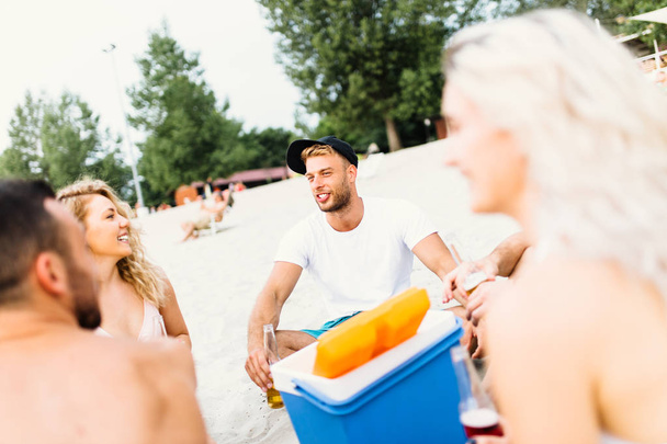 Group of attractive young people enjoying at beach, drinking and toasting. - Foto, afbeelding