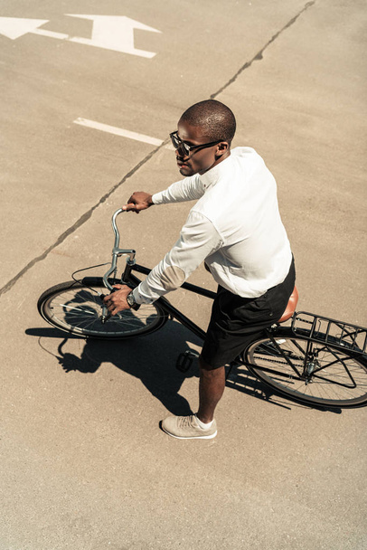 Handsome young african american man riding bike on street - Foto, imagen