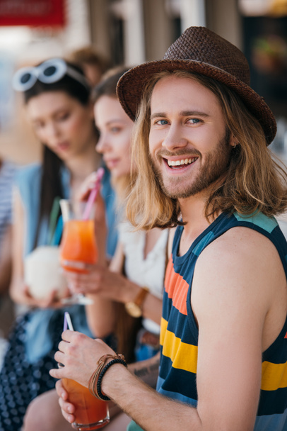 beau jeune homme souriant à la caméra en buvant un cocktail avec des amis au bar de la plage
 - Photo, image