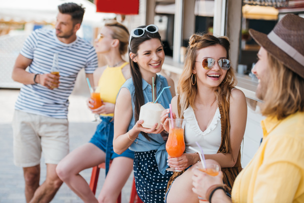 щасливі молоді чоловіки і жінки п'ють літні коктейлі в пляжному барі
 - Фото, зображення