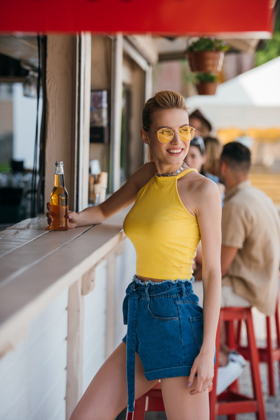 beautiful smiling girl holding glass of beer at beach bar - 写真・画像