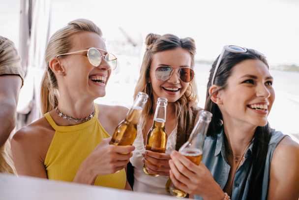 smiling young women drinking beer at beach bar - Foto, Imagem