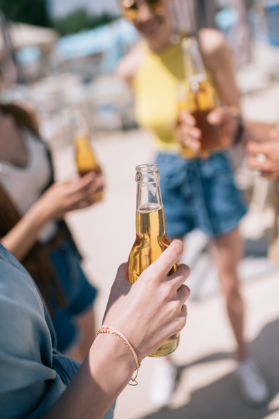 cropped shot of young people drinking beer at sunny summer day on beach - Foto, Imagen