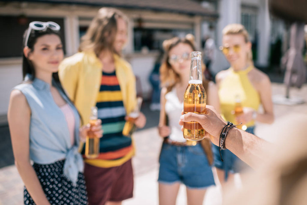 selective focus of young friends drinking beer on beach - Photo, Image