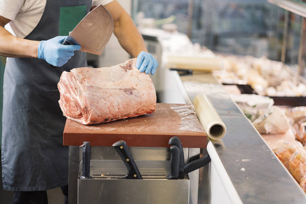 Carnicero con el cuchillo que corta la carne
 - Foto, Imagen