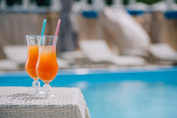 close-up view of glasses with summer cocktails and drinking straws at poolside - Photo, image