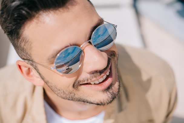 close-up portrait of handsome young man in sunglasses smiling outdoors - Foto, imagen