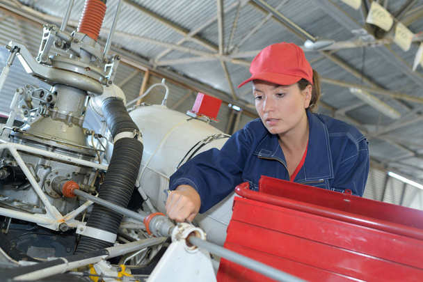 vrouwelijke monteur werken aan motor van de helikopter - Foto, afbeelding