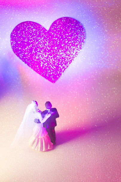 Γάμος ζευγάρι τούρτα γάμου κορυφή πλαστικές φιγούρες με σμόκιν κοστούμι βράδυ, λευκό νυφικό πέπλο. - Φωτογραφία, εικόνα