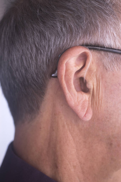 Dove senioren man moderne digitale spitstechnologie gehoorapparaat dragen in oor. - Foto, afbeelding