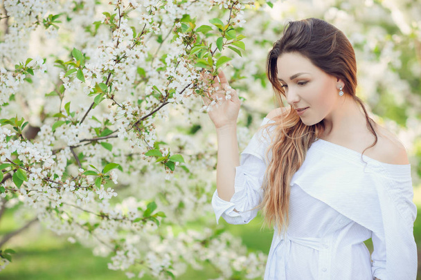 Genç güzel sarışın kadın çiçek açan badem bahçesinde bulunan beyaz çiçekler - Fotoğraf, Görsel