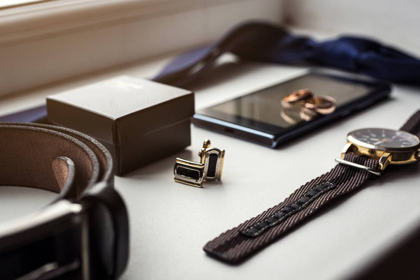 Different men's accessories such as: cufflinks, watches,  rings, belt, tie and phone - are on the table - Photo, Image