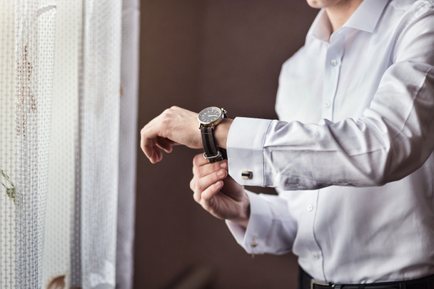 uomo d'affari controllare il tempo sul suo orologio da polso, l'uomo mettendo orologio a portata di mano, sposo si prepara al mattino prima della cerimonia di matrimonio - Foto, immagini