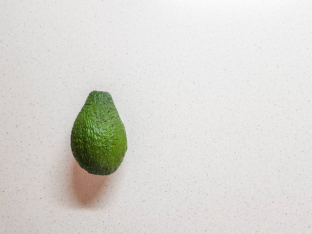 Спелый авокадо в руке. Белая пекарня. Вид сбоку
 - Фото, изображение