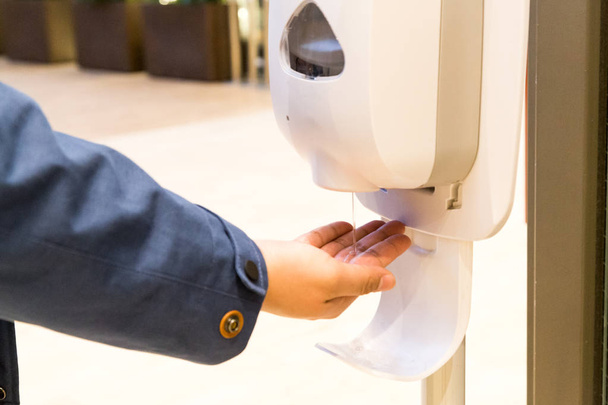 Person cleaning hand with anti-bacterial hand disinfectant sanitizer dispenser in public mall in Japan - Photo, Image