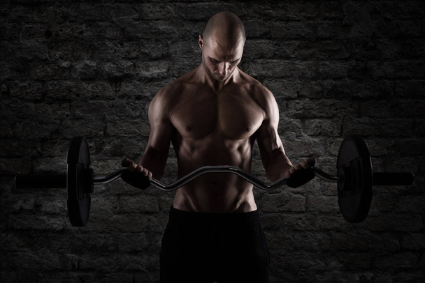 Athletic man training biceps at the gym - Photo, Image